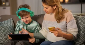 Mom showing something to her son, who's wearing a pair of headphones, on a tablet